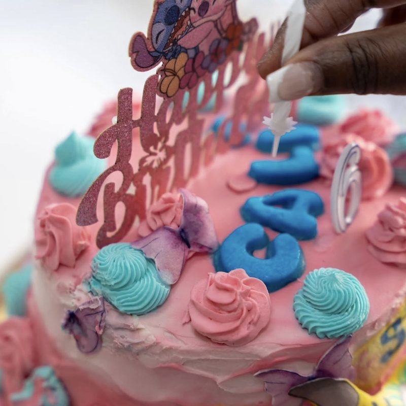 Gâteau d'anniversaire décoré de rosaces de crème et de lettres en pâte à sucre